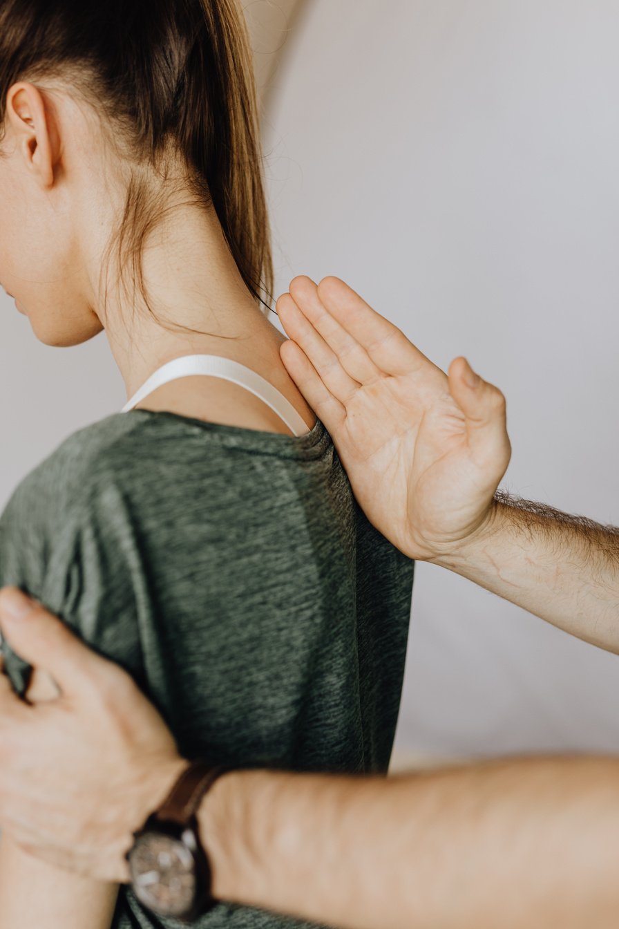 Crop faceless chiropractor checking up back of female patient